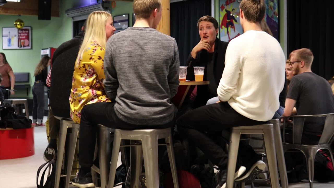 Studerende med øl i plastikkrus sidder om et bord og snakker