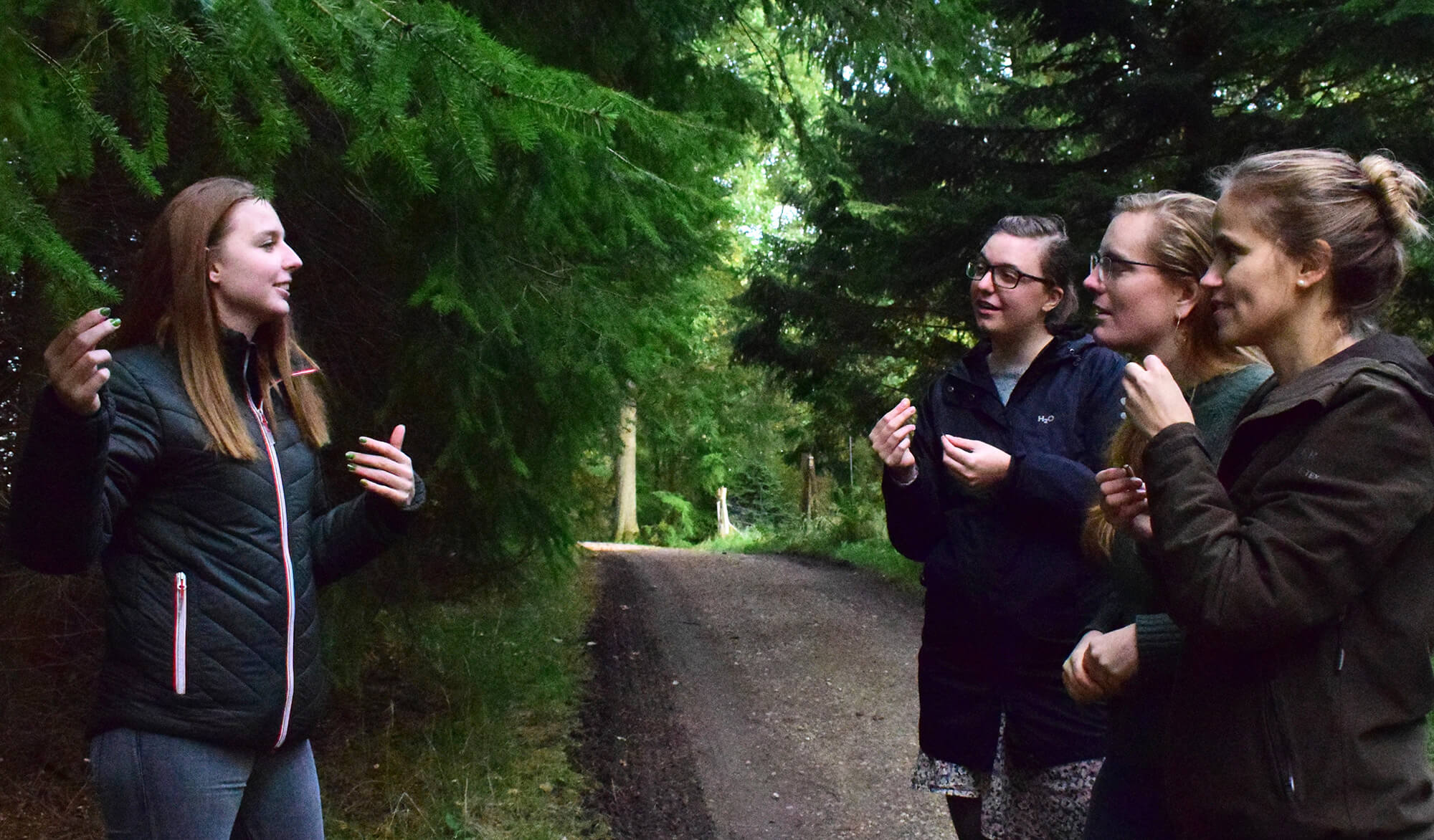 En natur- og kulturformidler guider og fortæller for tre gæster i skoven