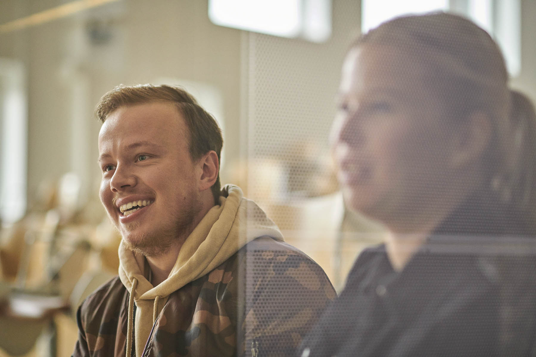 To studerende til pædagogisk assistent sidder i et klasselokale og smiler