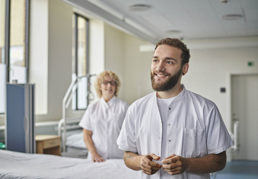 En mandlig sygeplejerskestuderende i kirtel smiler