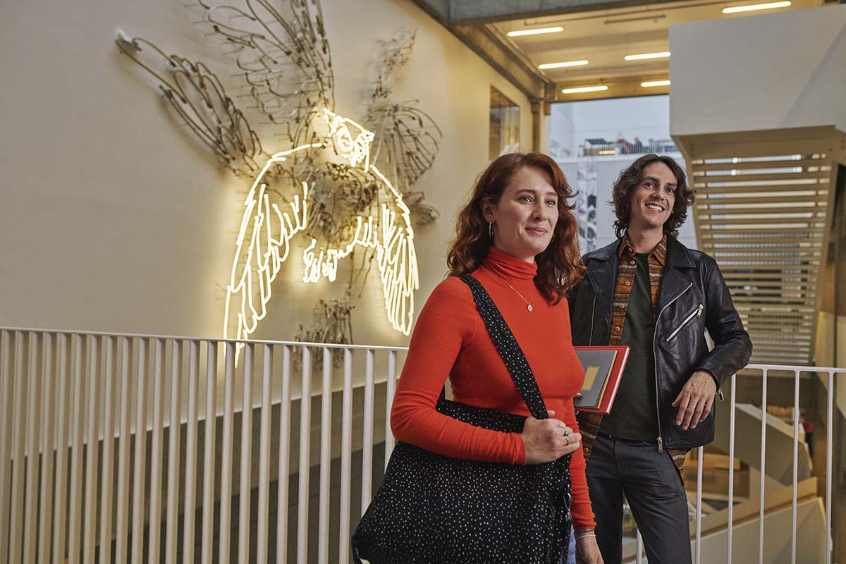 To studerende, en kvinde og en mand står foran kunstværket "Orakel", som forestiller en ugle og hænger på Calrsberg campus