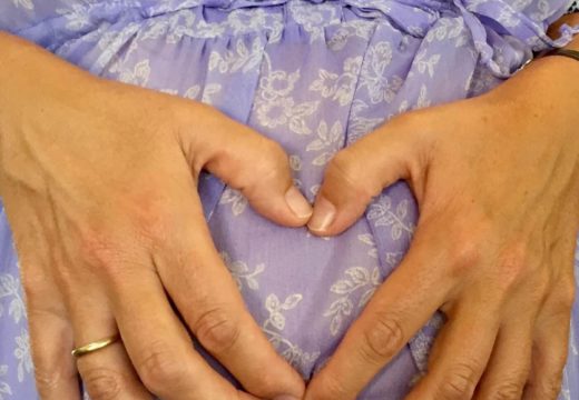 Fødselsforberedelse - kvinde i blå kjole holder sig om sin gravide mave