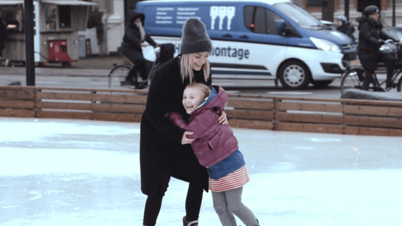 Buddie og barn står på skøjter sammen