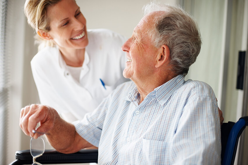 Ældre mand taler med smilende sygeplejerske