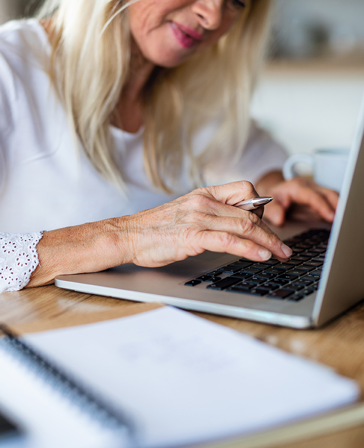 Unrecognizable senior woman with laptop indoors in home office, working.