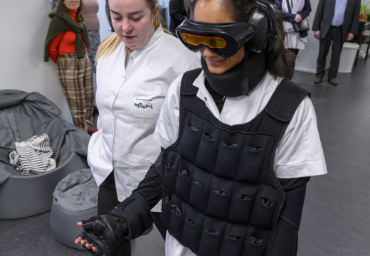En studerende i udstyr, der skal simulere en svagere krop. Bl.a. en tung vest, vægte om armene og et høreværn.