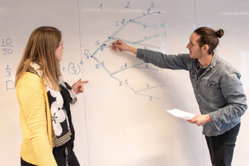 To lærerstuderende laver udregning på whiteboard