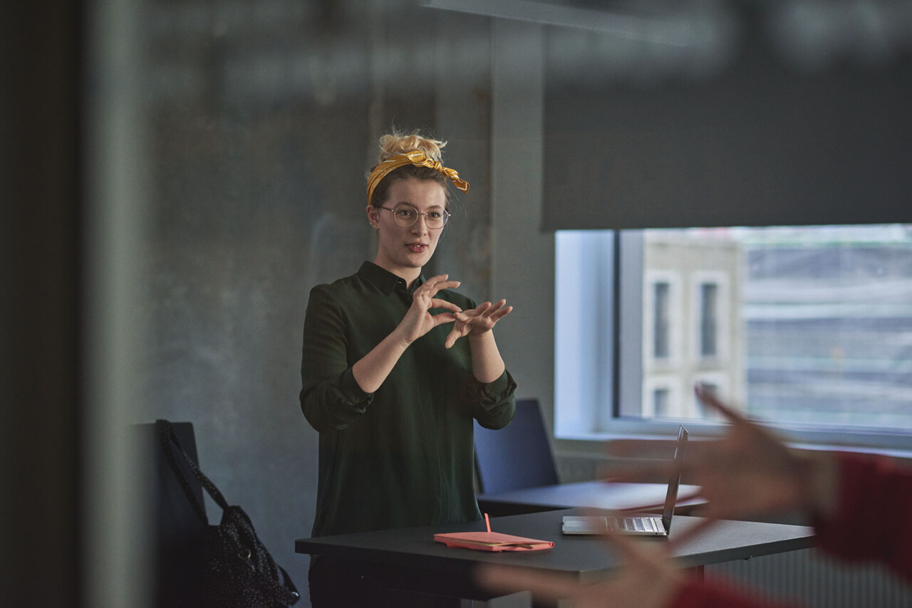 Tegnsprogs- og skrivetolk, der kommunikerer med tegnsprog.
