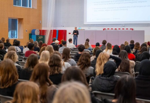 En oplægsholder taler ud til en stor forsamling