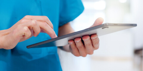 hænderne på en sygeplejerske, der holder en ipad