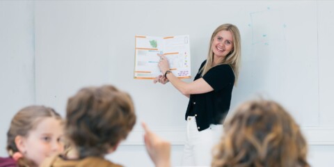 Lærer viser en bog frem for en klasse med børn.