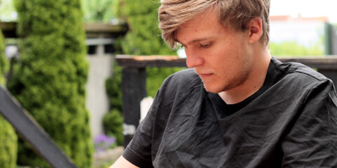 Ung mand sidder med sin telefon